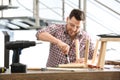 Handsome working man repairing wooden stool at table indoors