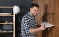 Handsome working man setting shelf indoors