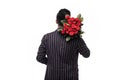 Handsome yound indian man in suit is standing with red roses behind the back on white background