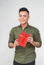 Handsome yound man on grey background with red gift box in hands