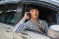 A handsome young-adult Asian man in casual outfit is talking on the phone while driving a car Royalty Free Stock Photo