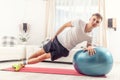 Handsome young adult doing bodyweight workout in the living room, holding a side plank position on elbow, with rear leg extended