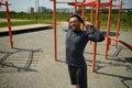 Handsome young adult 40 years old European sporty man stretching arms behind his back before training on the sportsground in open