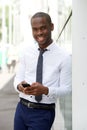 Handsome young african american businessman smiling with mobile phone in city Royalty Free Stock Photo