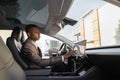 Handsome young African American businessman touches the touchscreen in his new high-tech electric vehicle while drinking Royalty Free Stock Photo