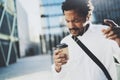 Handsome young African American man in headphone walking at sunny city and enjoying to listen to music on his smartphone Royalty Free Stock Photo