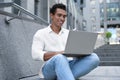 Handsome young African-American man with laptop sitting on stairs Royalty Free Stock Photo