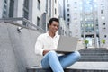 Handsome young -American man with laptop sitting on stairs outdoors Royalty Free Stock Photo