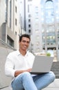 Handsome young African-American man with laptop sitting on stairs Royalty Free Stock Photo