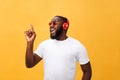 Handsome young African American man listening and smiling with music on his mobile device. over yellow Royalty Free Stock Photo