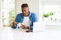 Handsome young african business man eating delivery asian food and working using computer, enjoying noodles smiling Royalty Free Stock Photo