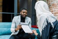 Handsome young African businessman smiling and offering business contract to his pretty female Muslim business partner Royalty Free Stock Photo