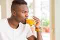 Handsome young african man drinking a glass of fresh natural orange juice enjoying fruit refreshment Royalty Free Stock Photo