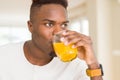 Handsome young african man drinking a glass of fresh natural orange juice enjoying fruit refreshment Royalty Free Stock Photo