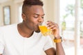 Handsome young african man drinking a glass of fresh natural orange juice enjoying fruit refreshment Royalty Free Stock Photo