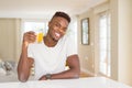 Handsome young african man drinking a glass of fresh natural orange juice and smiling Royalty Free Stock Photo