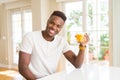 Handsome young african man drinking a glass of fresh natural orange juice and smiling Royalty Free Stock Photo