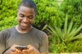 handsome young african man viewing content on his mobile phone, smiling while typing and surfing the internet