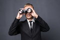 Handsome young american businessman using binoculars in office on gray background Royalty Free Stock Photo