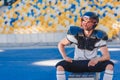 handsome young american football player sitting on bench