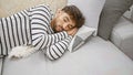 Handsome young arab man, with a relaxed beard, comfortably lying on his cozy living room sofa, finding comfort in the interior as