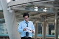 Handsome young Asian business man looking paperwork or charts in his hands between walking to the office Royalty Free Stock Photo