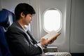 Handsome Asian businessman reading a book during the flight for his business trip Royalty Free Stock Photo