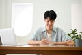 Handsome young Asian male college student focusing on his homework, taking notes Royalty Free Stock Photo