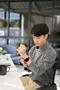 Handsome young Asian male developer or business office worker wearing his smartwatch Royalty Free Stock Photo