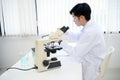 A handsome Asian male scientist examining a virus specimen under a microscope in the lab Royalty Free Stock Photo