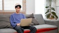 Handsome young Asian man using laptop computer on sofa in his minimal living room Royalty Free Stock Photo