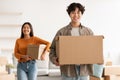 Handsome young Asian man with his lovely girlfriend carrying carton boxes, unpacking in their new home, copy space Royalty Free Stock Photo