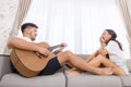 Handsome young asian man playing acoustic guitar and singing for his beautiful girlfriend Royalty Free Stock Photo