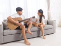 Handsome young asian man playing acoustic guitar and singing for his beautiful girlfriend Royalty Free Stock Photo