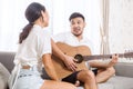 Handsome young asian man playing acoustic guitar and singing for his beautiful girlfriend Royalty Free Stock Photo