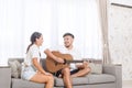 Handsome young asian man playing acoustic guitar and singing for his beautiful girlfriend Royalty Free Stock Photo