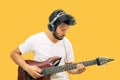 Handsome young asian men playing guitar and  listen music with headphones   on yellow background Royalty Free Stock Photo