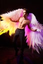 Handsome young athletic man with a bare torso who looks like an angel with white wings. Model dancer posing in a dark Royalty Free Stock Photo