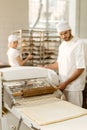 handsome young baker working with industrial dough roller