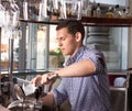 Handsome young bartender behind the bar counter holding steel ic Royalty Free Stock Photo