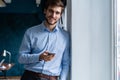 Handsome young bearded business man in office using mobile phone indoors. Royalty Free Stock Photo