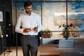 Handsome young bearded business man in office using mobile phone indoors. Royalty Free Stock Photo