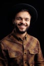 Handsome young bearded hipster in brown shirt smiling over black background. Royalty Free Stock Photo