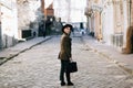 Handsome young bearded hipster man guy in hat Fedora on street with suitcase. Retro vintage fashion look Royalty Free Stock Photo