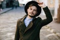 Handsome young bearded hipster man guy in hat Fedora on street with suitcase. Retro vintage fashion look Royalty Free Stock Photo