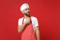 Handsome young bearded male chef cook baker man in striped apron white t-shirt toque chefs hat posing isolated on red Royalty Free Stock Photo