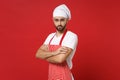 Handsome young bearded male chef cook baker man in striped apron white t-shirt toque chefs hat posing isolated on red Royalty Free Stock Photo