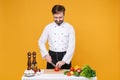 Handsome young bearded male chef cook or baker man in white uniform shirt isolated on yellow background. Cooking food Royalty Free Stock Photo