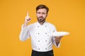 Handsome young bearded male chef cook or baker man in white uniform shirt posing isolated on yellow background. Cooking Royalty Free Stock Photo