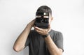 Handsome young bearded man in a black shirt holding vintage old-fashioned film camera on a white background and looking Royalty Free Stock Photo